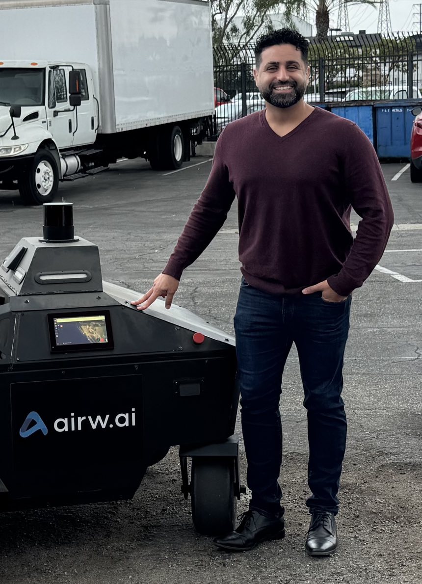 Amir Emadi standing beside Airwai's VEGA autonomous ground vehicle.